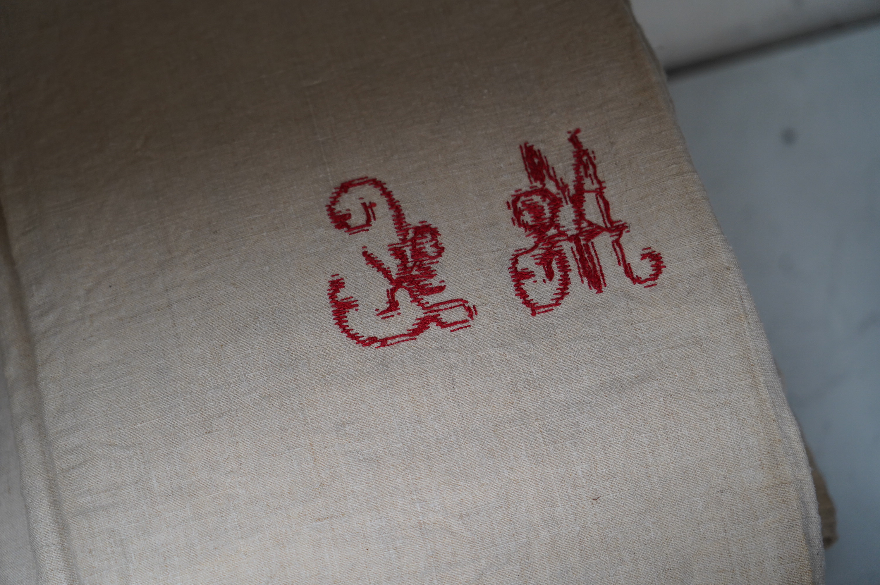 Fourteen French provincial coarse linen sheets, mostly with red embroidered monograms